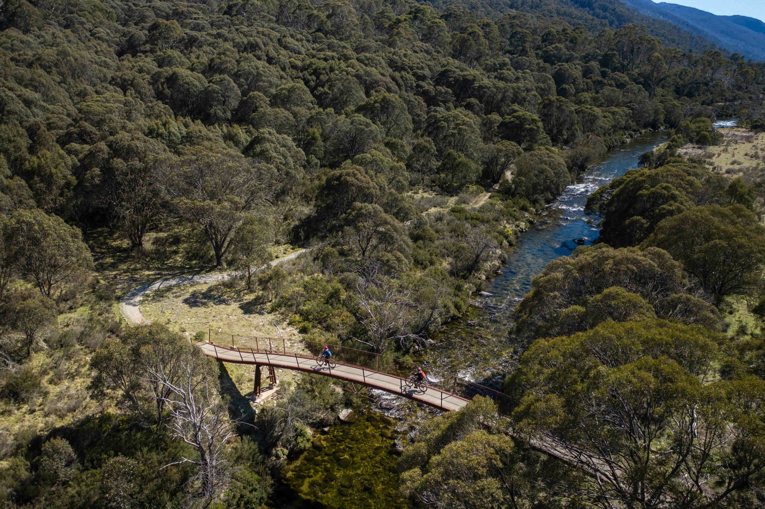 Riders cross a bridge on the Thredbo Valley Track