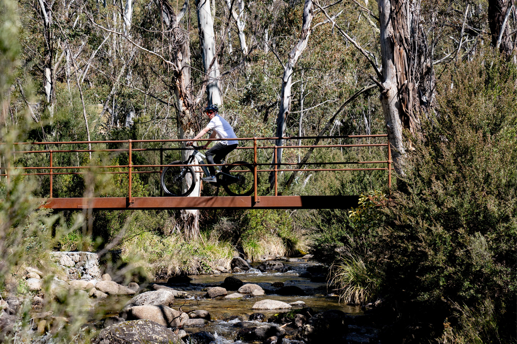 Bike rider riding over river on bridge